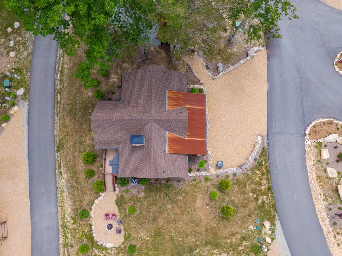 This image showcases the exterior of a home at Eagles Nest, with its thoughtfully designed roof, a landscaped yard, a gravel driveway, and a welcoming outdoor seating area. The space is peaceful, open, and perfect for gatherings or relaxing after a day of adventures.