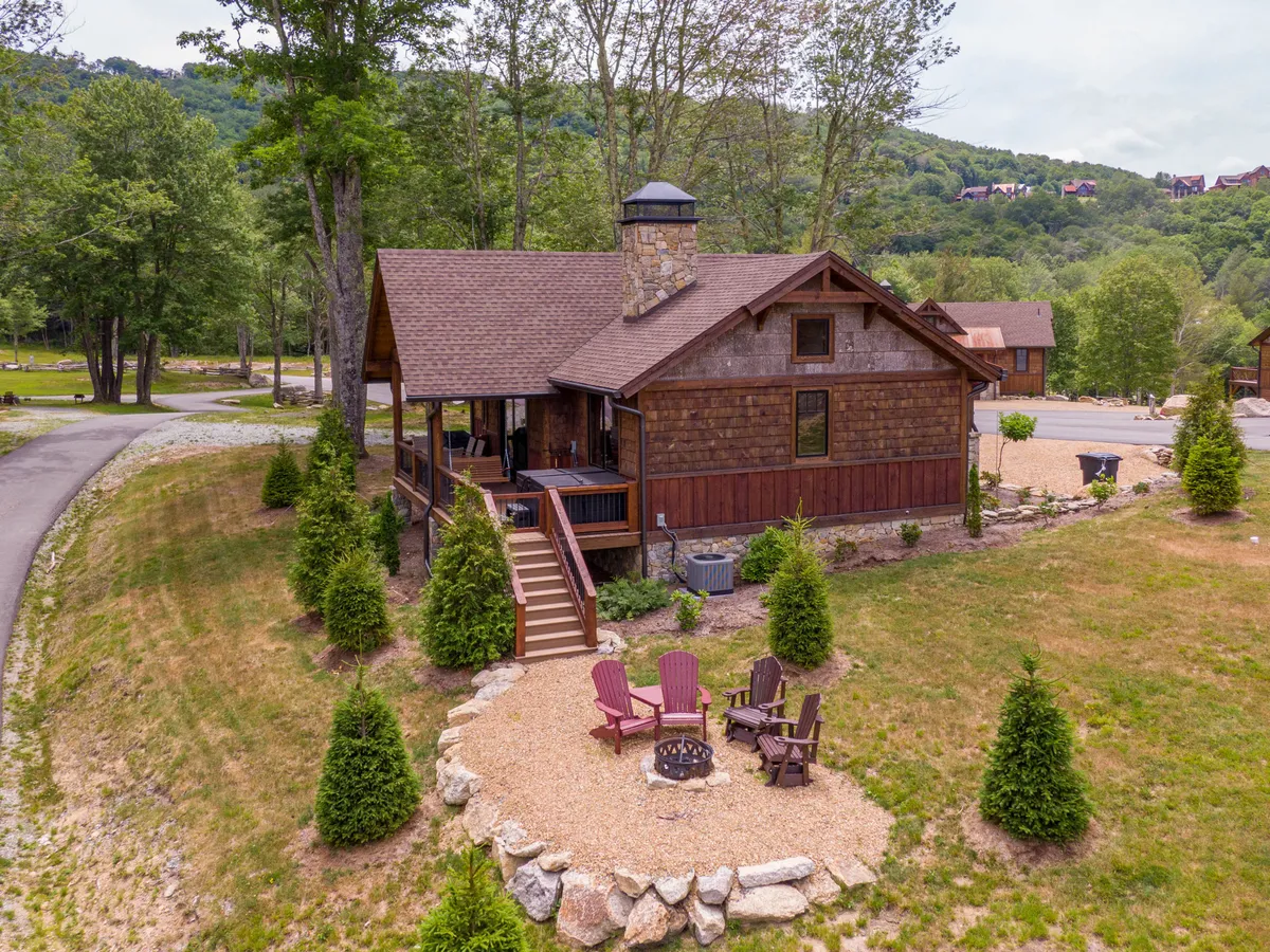 An inviting scene of the cabin exterior, with a fire pit surrounded by seating and nestled among tall trees. The space is perfect for social gatherings, stargazing, or sharing stories by the fire after an active day exploring the outdoors.